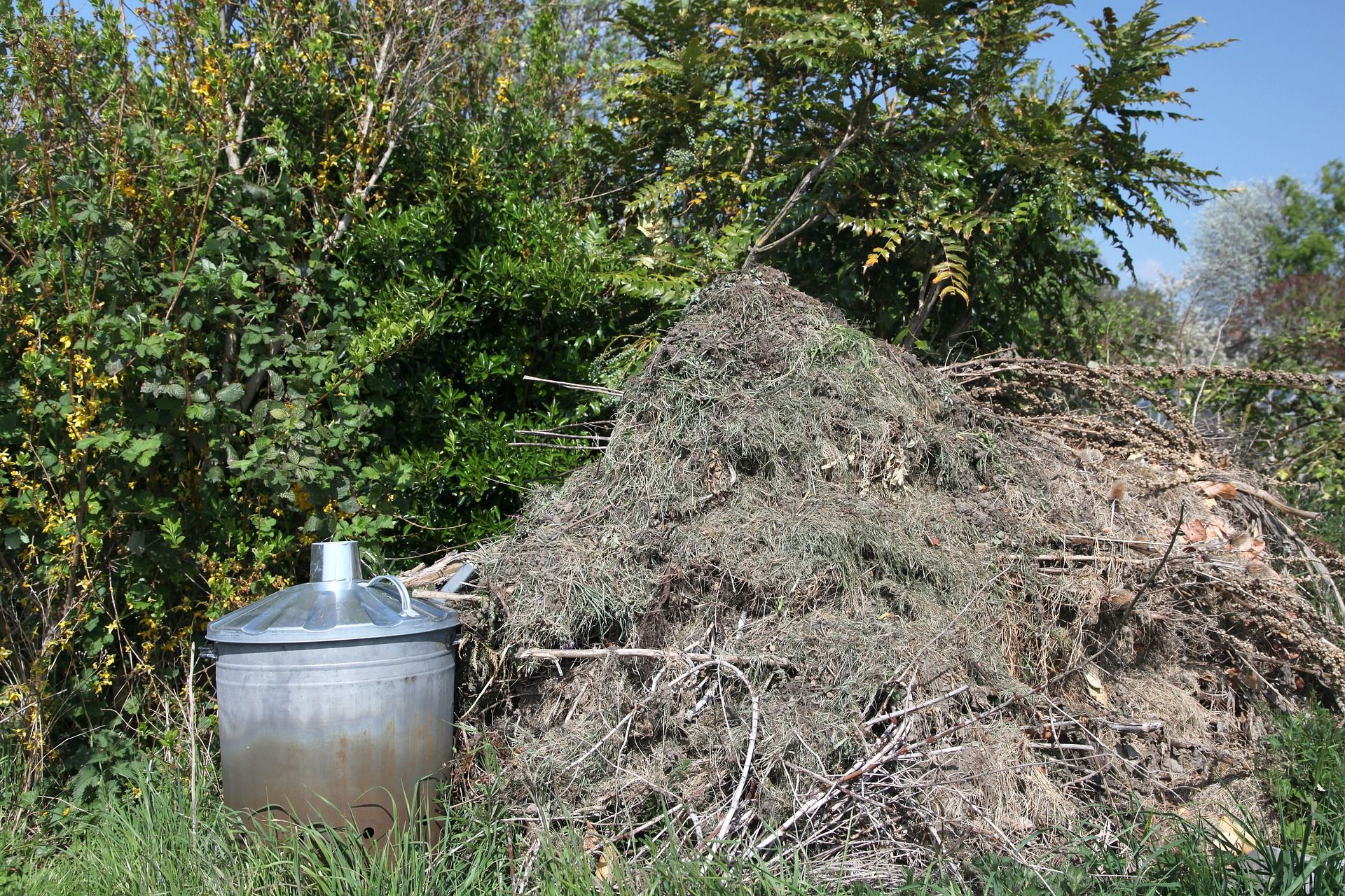 A messy pile of composting next to a metal bin